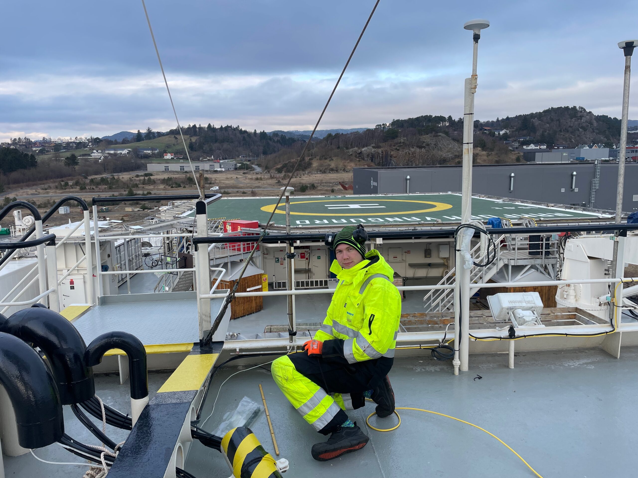 Tekniker på dekk med helipad i bakgrunnen